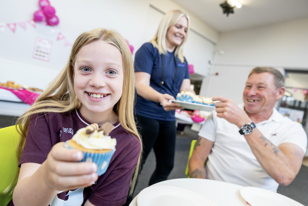Young girl and her dad being served some cupcakes by one of the organisers